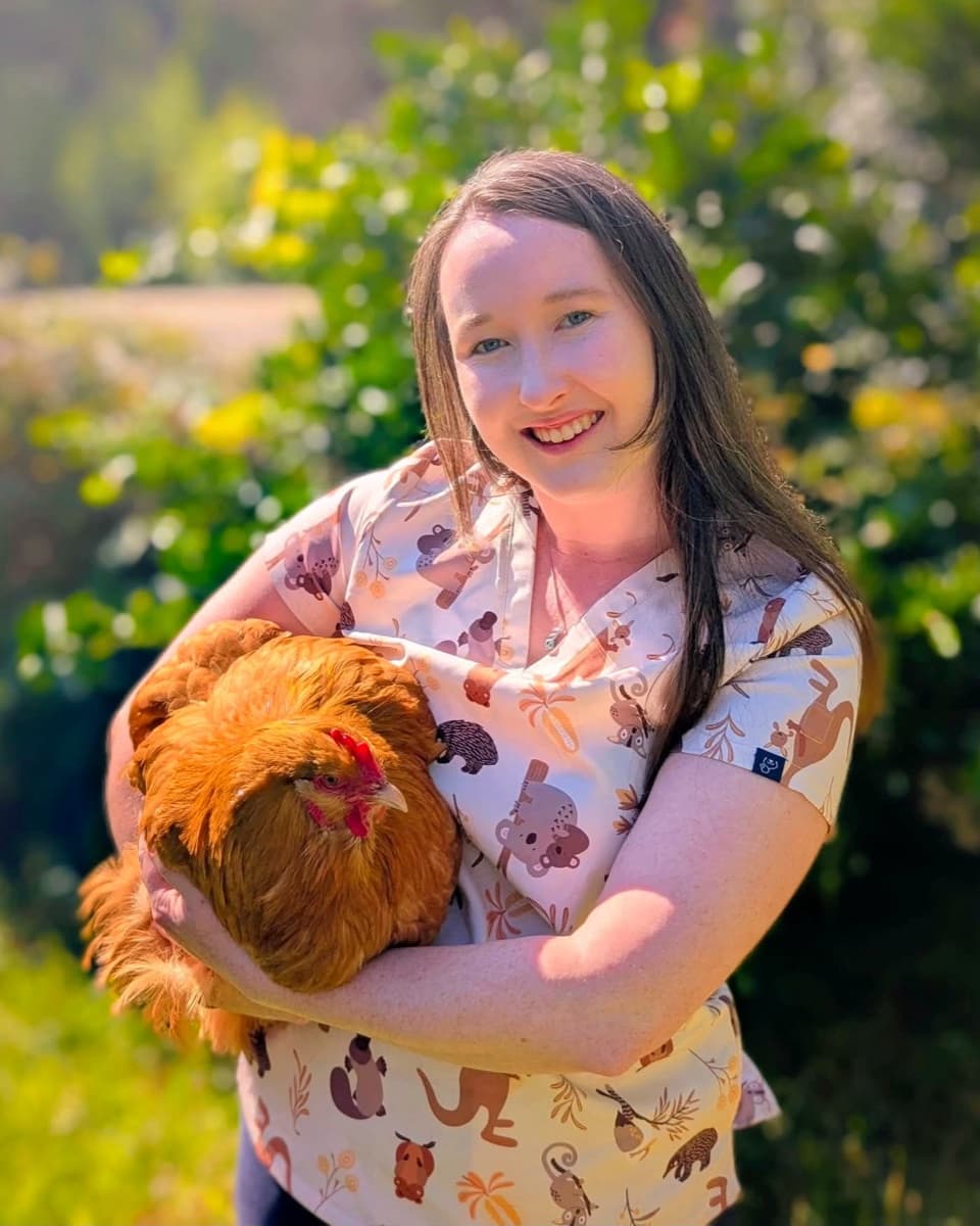 Dr Sarah Webb outdoors, holding one of her hens